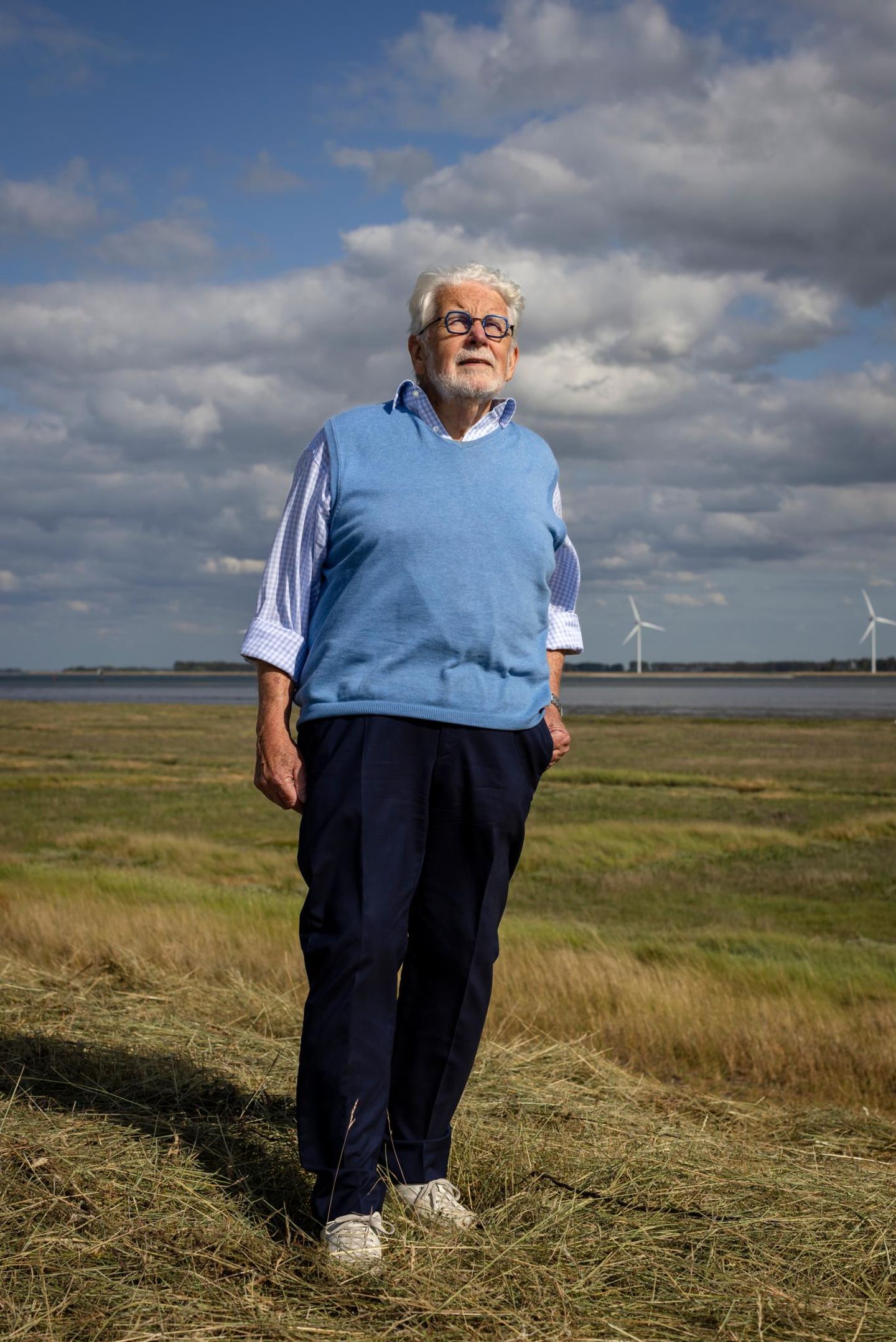EIn Mann steht auf einem Feld, im Hintergrund sind Windräder zu sehen