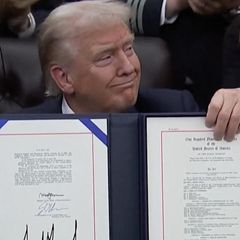 Donald Trump hält mit selbstbewussten Blickes das signierte Abkommen in der Hand.