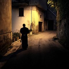 Ein Priester läuft durch eine beleuchtete Gasse