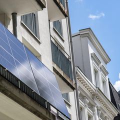 Ein Balkonkraftwerk an einem Balkon eines weißen Mehrfamilienhauses.