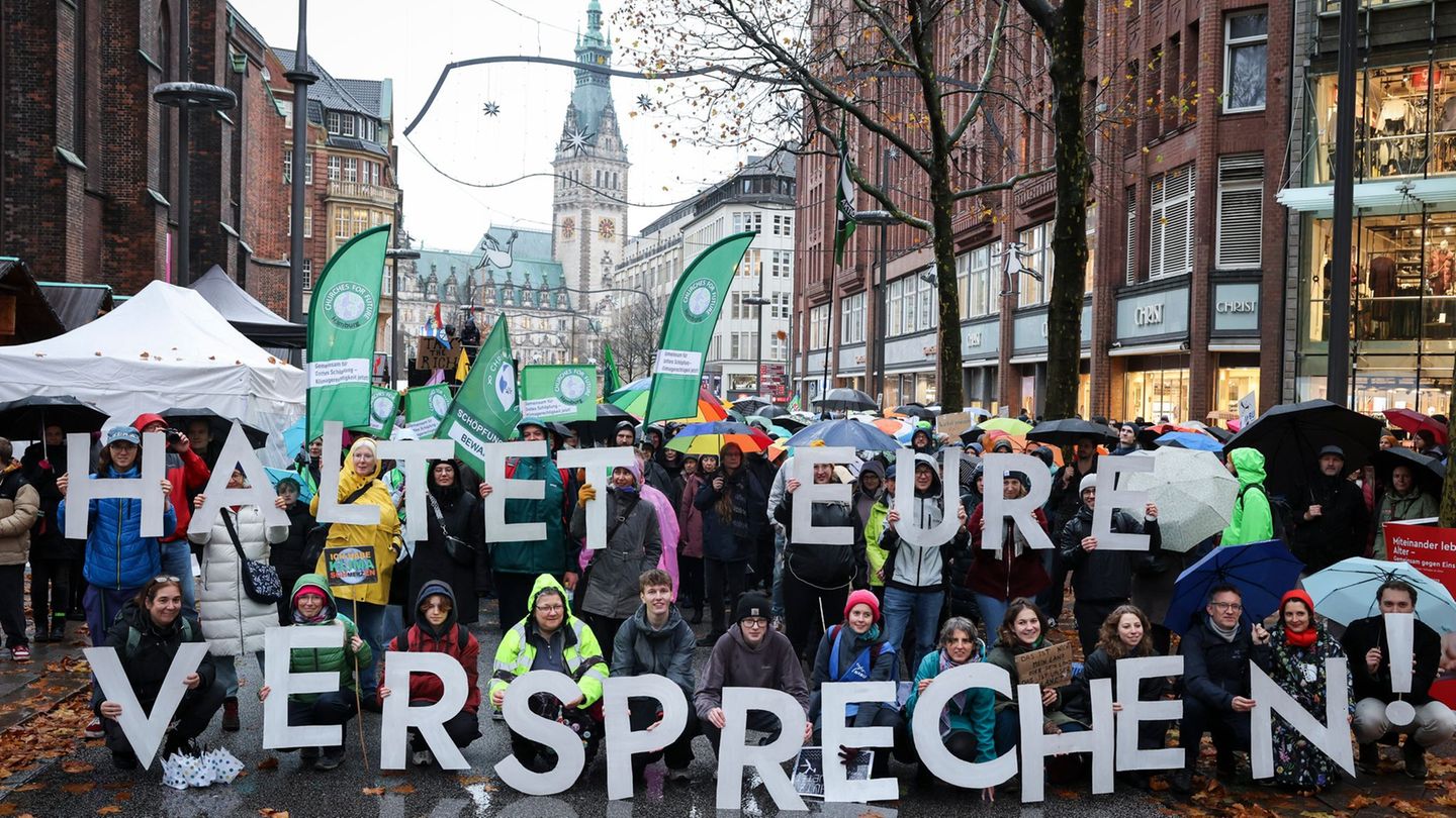 Teilnehmer der Demonstration in Hamburg halten Buchstaben, die einen Slogan ergeben. Foto: Christian Charisius/dpa