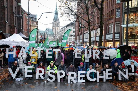 Teilnehmer der Demonstration in Hamburg halten Buchstaben, die einen Slogan ergeben. Foto: Christian Charisius/dpa