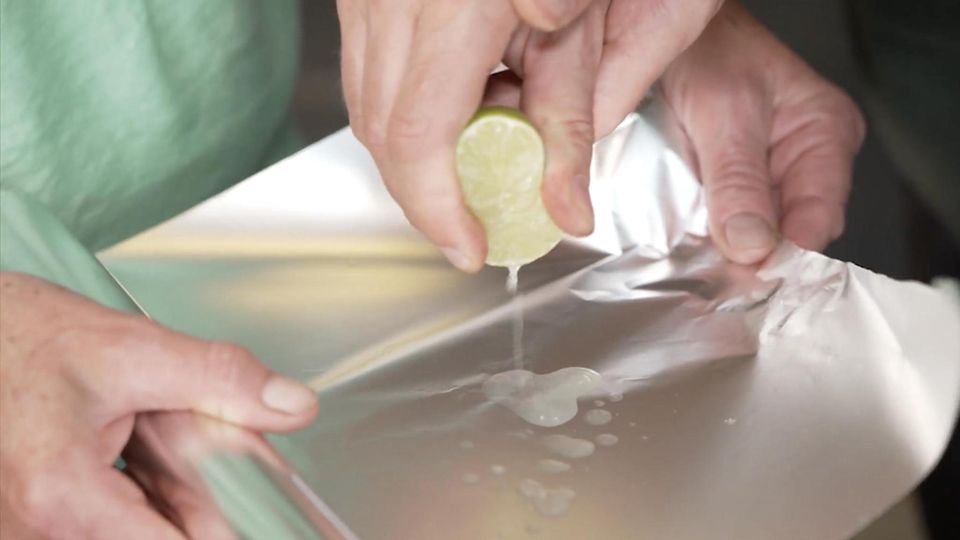 Eine Limette wird über Alufolie ausgedrückt.