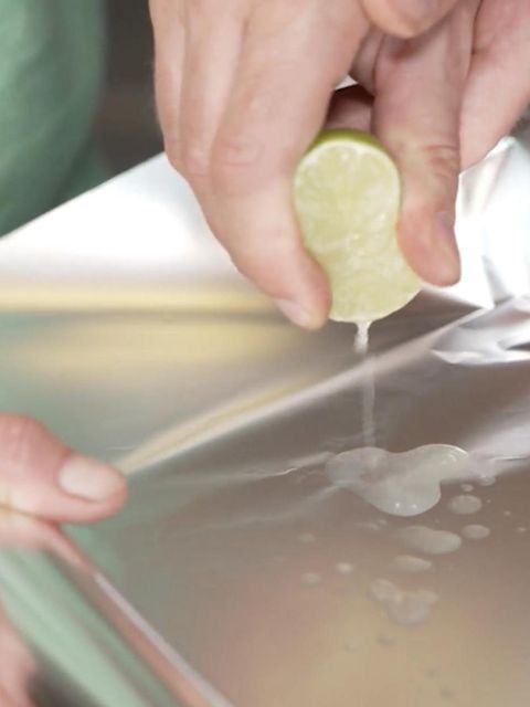 Eine Limette wird über Alufolie ausgedrückt.