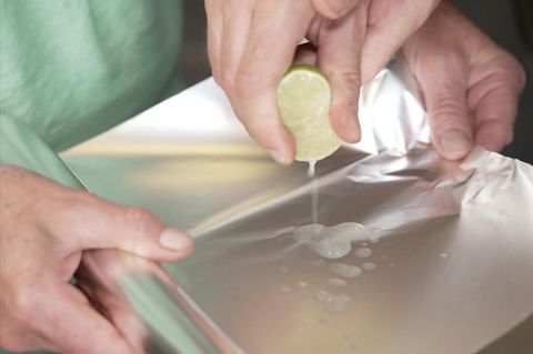 Eine Limette wird über Alufolie ausgedrückt.