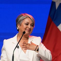 Jeannette Jara, Präsidentschaftskandidatin in Chile, fasst sich auf einer Bühne lächelnd mit links ans Herz