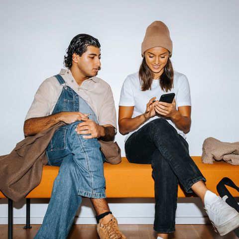 Eine junger Mann und eine junge Frau sitzen mit überkreuzten Beinen