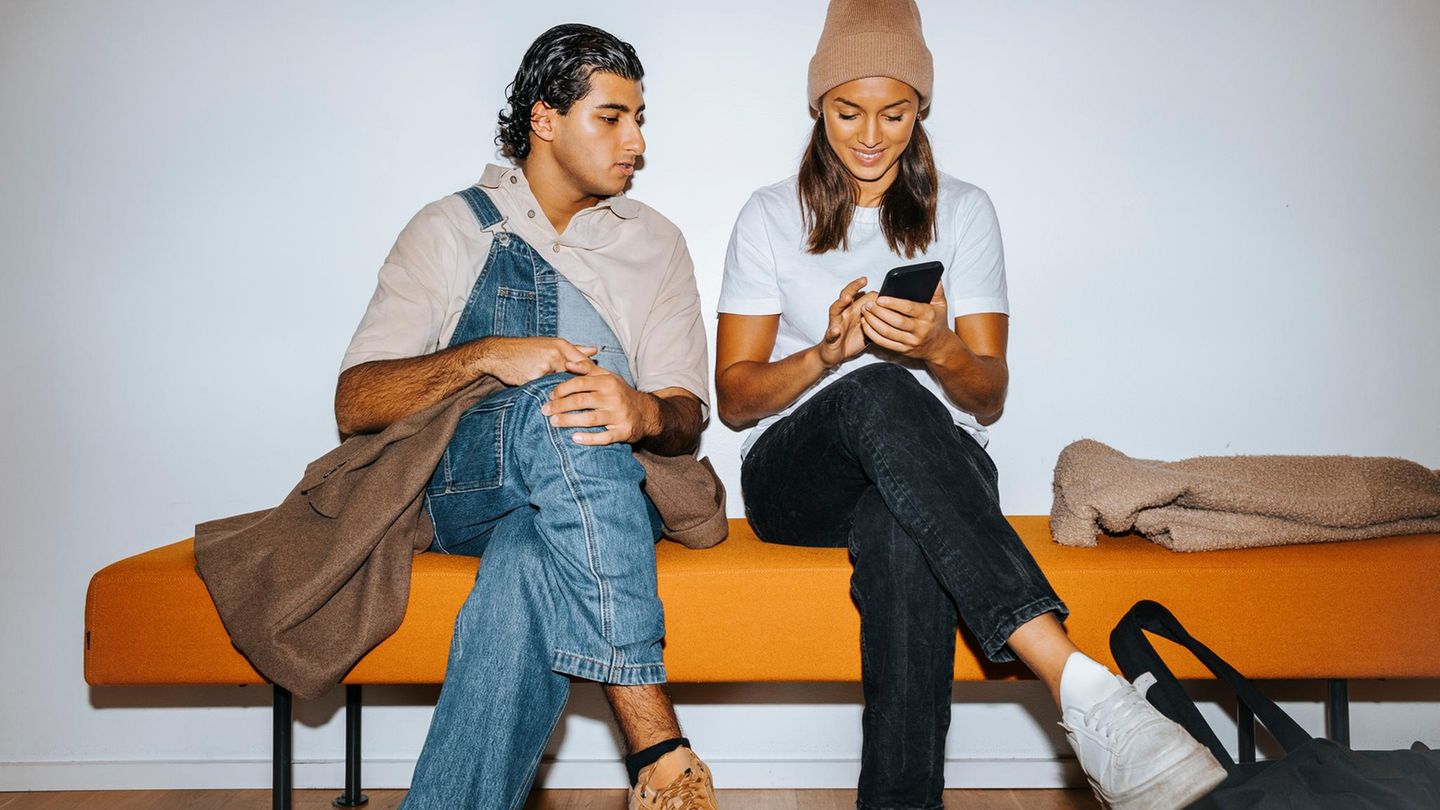 Eine junger Mann und eine junge Frau sitzen mit überkreuzten Beinen