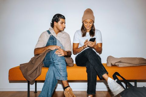 Eine junger Mann und eine junge Frau sitzen mit überkreuzten Beinen