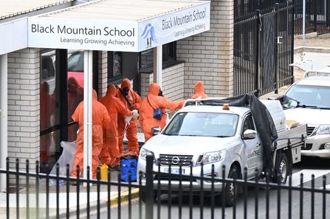 Menschen in Schutzanzügen vor der Black Mountain School in Australiens Hauptstadt Canberra