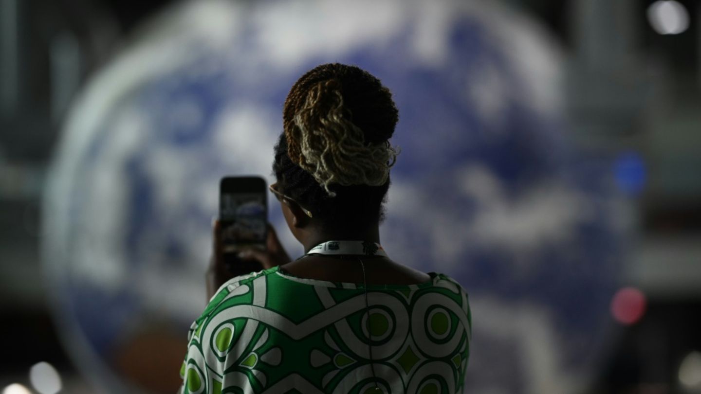 Eine COP30-Teilnehmerin vor einer Weltkugel in Belém