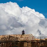 Ein Bauarbeiter macht eine Verschnaufpause, während sich Wolken über einem Hausbauprojekt auftürmen