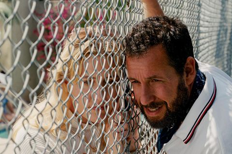 Adam Sandler lehnt an einem Maschendrahtzaun in einer Filmszene