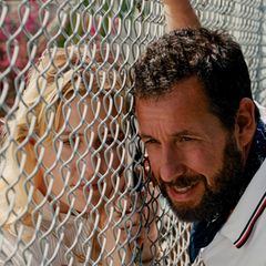 Adam Sandler lehnt an einem Maschendrahtzaun in einer Filmszene