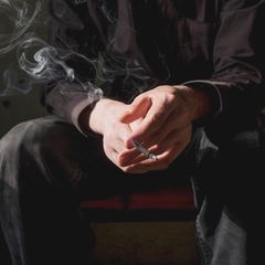 Mann beim Rauchen mit Zigarette in der Hand