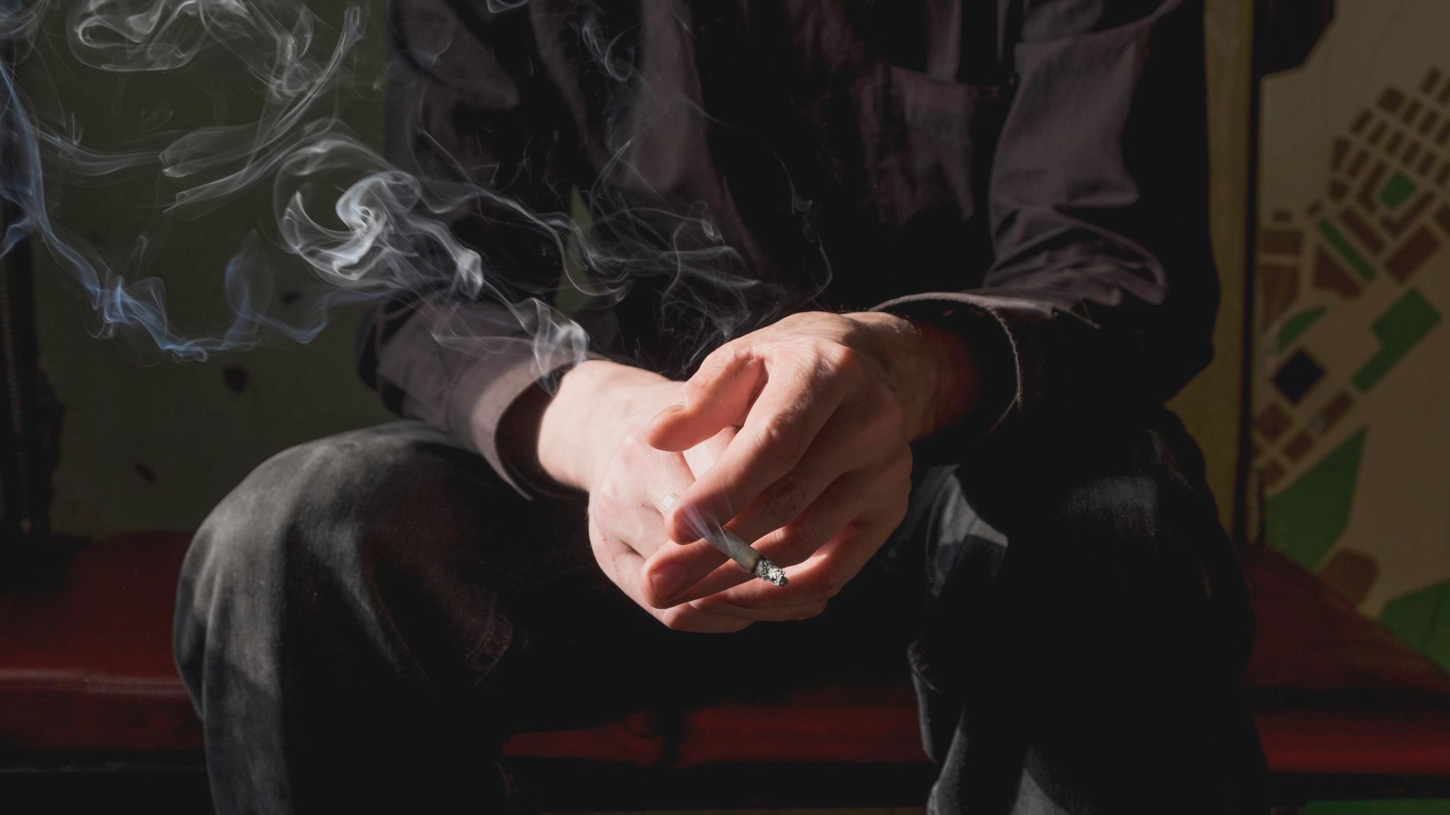 Mann beim Rauchen mit Zigarette in der Hand