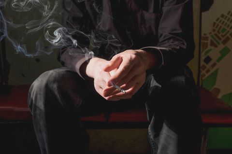 Mann beim Rauchen mit Zigarette in der Hand