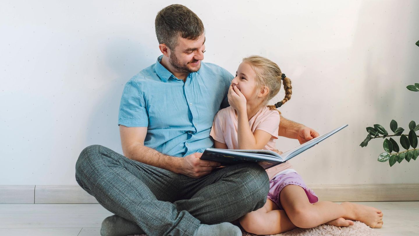 Vorlesen: Mann mit Mädchen, sie lacht, beim Vorlesen