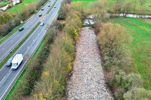 Neben der Autobahn zieht sich ein fast identisch großer Streifen Müll, versteckt hinter ein paar Bäumen.