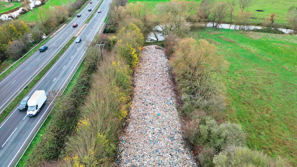 Neben der Autobahn zieht sich ein fast identisch großer Streifen Müll, versteckt hinter ein paar Bäumen.