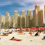 Menschenmenge am Strand mit Hochhäusern im Hintergrund