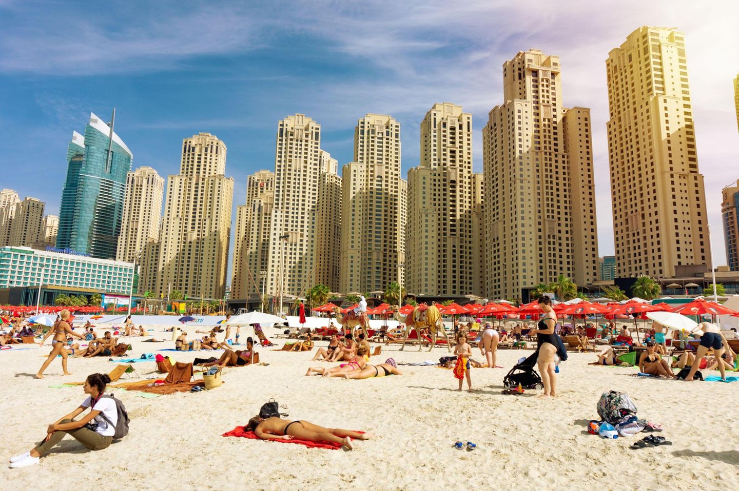 Menschenmenge am Strand mit Hochhäusern im Hintergrund