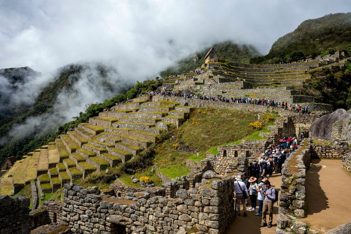 Schlange an Menschen auf den Wegen einer Ruine am Berg zu Machu Picchu