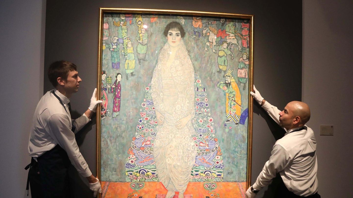 Zwei Mitarbeiter eines Auktionshauses hängen das Gemälde "Portrait of Elisabeth Lederer" von Gustav Klimt auf
