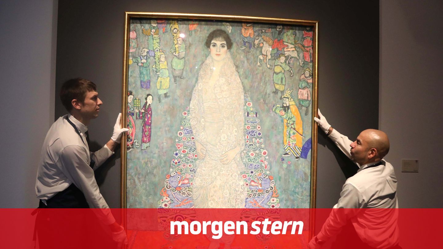 Zwei Mitarbeiter hängen ein Gemälde von Gustav Klimt auf