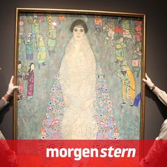 Zwei Mitarbeiter hängen ein Gemälde von Gustav Klimt auf