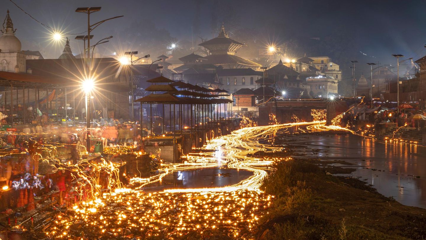 Katmandu, Nepal. Gläubige Hindus lassen am Bagmati-Fluss Öllampen zu Ehren ihrer verstorbenen Familienmitglieder schwimmen, während sie das Balachaturdashi-Fest begehen. Am nächsten Morgen verstreuen die Familienangehörigen Satabij, Reis, Gerste, Sesam, Weizen, Kichererbsen, Mais und Fingerhirse. Die Samen werden in dem Glauben ausgesät, dass die verstorbenen Seelen Erlösung finden
