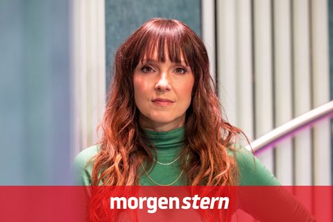 Die Komikerin Carolin Kebekus lehnt in einem grünen Pulli mit der rechten Schulter an einer Wand