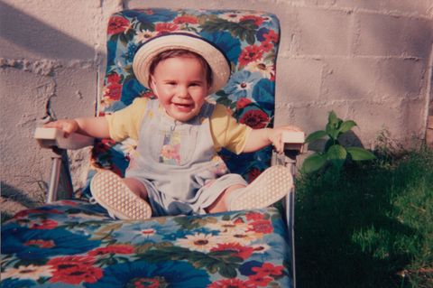 Symbolbild Kindheitserinnerungen: Kleinkind in den 90ern sitzt auf einem geblümten Gartenstuhl