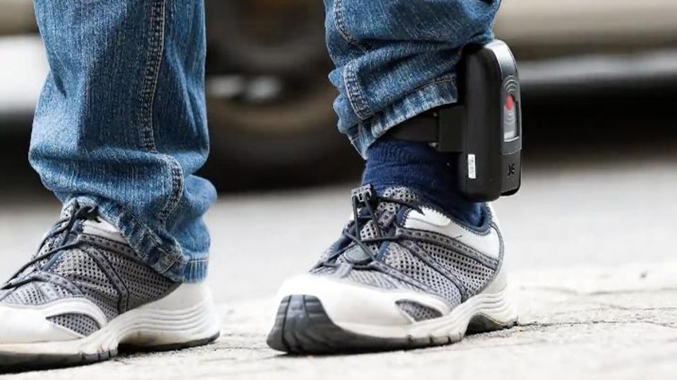 Ein Mann mit einer Fußfessel. Die Hose ist seitlich über dem Gerät hochgezogen.