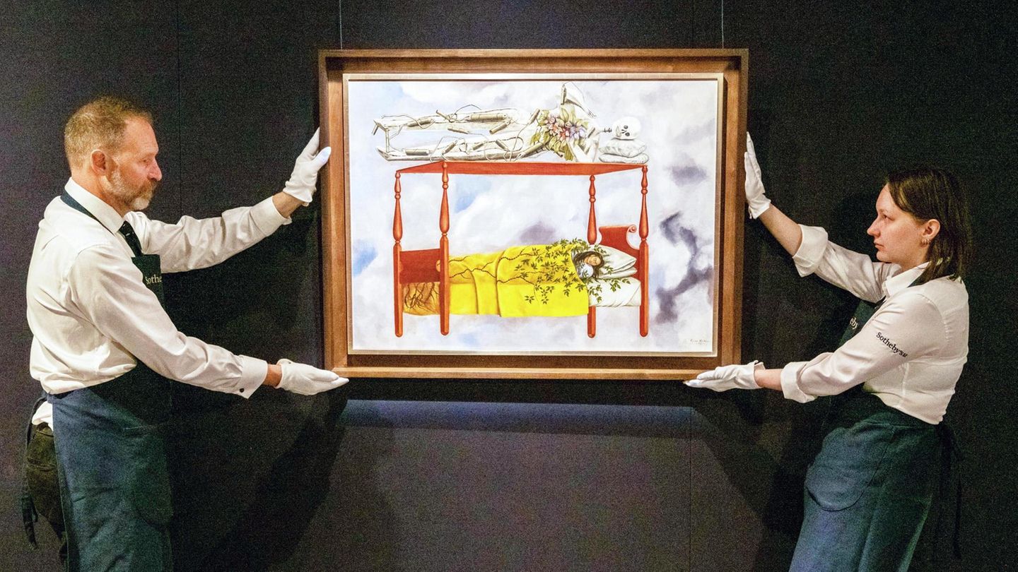 Zwei Mitarbeitende eines Auktionshauses hängen rücken das Gemälde "El sueño (la cama)" von Frida Kahlo zurecht