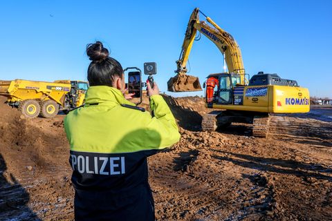Eine Polizistin filmt einen Bagger beim Spatenstich auf dem Gelände des neuen Landeskriminalamts. Foto: Peter Gercke/dpa