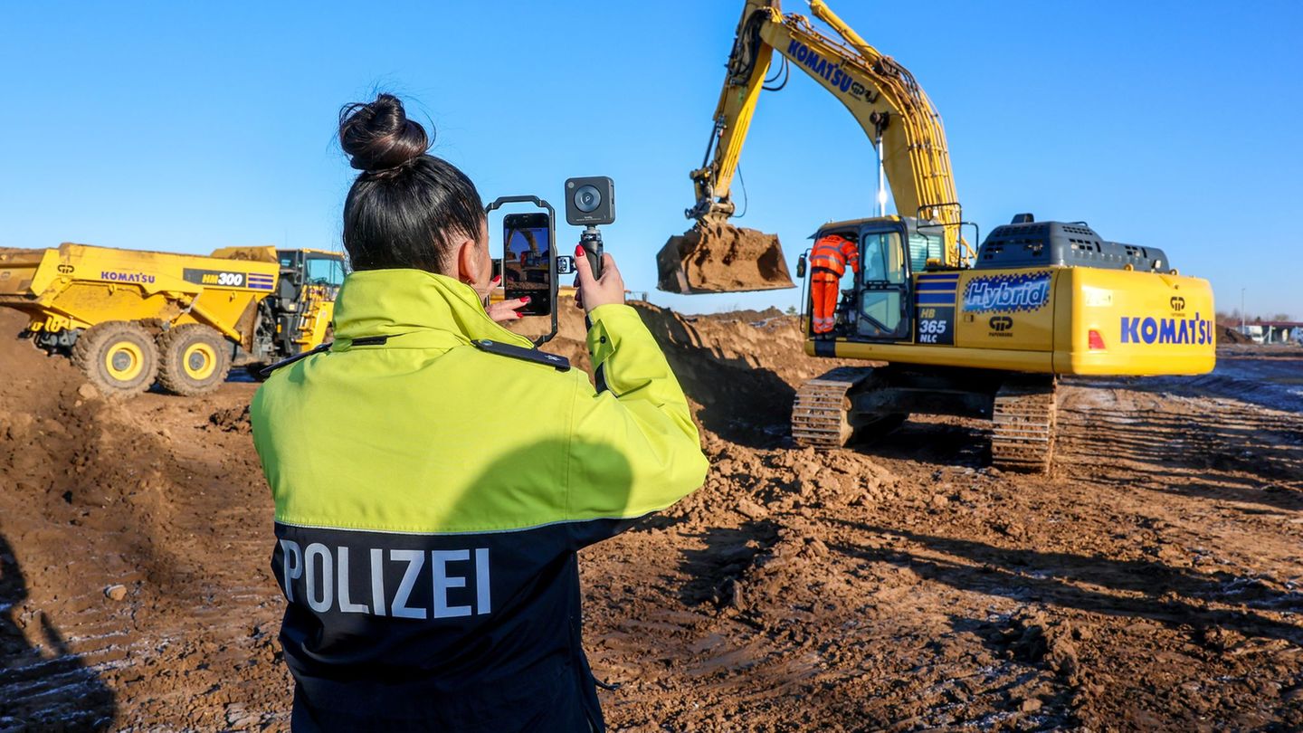 Eine Polizistin filmt einen Bagger beim Spatenstich auf dem Gelände des neuen Landeskriminalamts. Foto: Peter Gercke/dpa