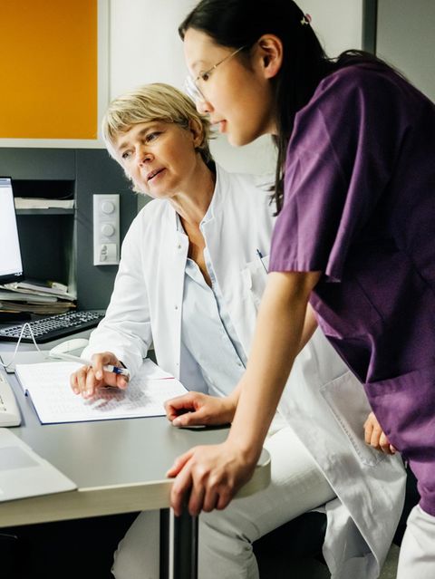 Klinikpersonal beugen sich über Patienten-Akten