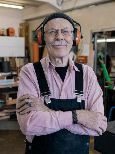 Ein älterer Herr in einer Werkstatt trägt Gehörschutz