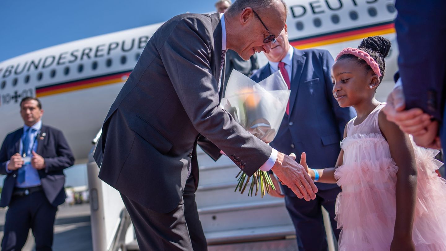 Kanzler Friedrich Merz wird auf dem Flughafen von Johannesburg von einem Mädchen begrüßt. Foto: Michael Kappeler/dpa