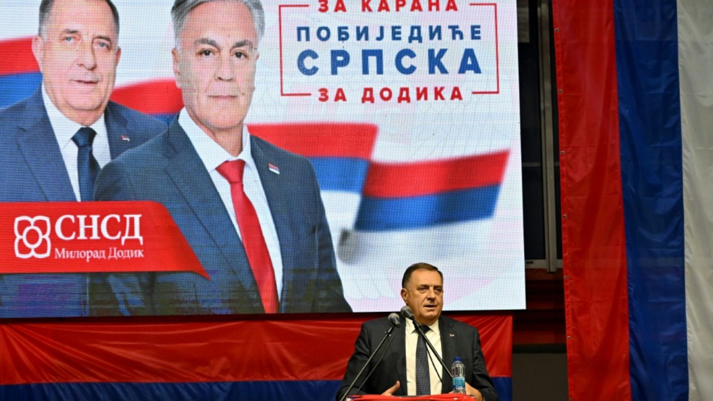 Dodik im Wahlkampf vor einem Plakat mit Karan