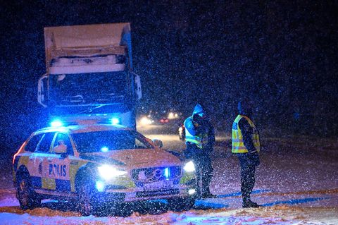 Zwei Polizisten in Schweden stehen im Schneetreiben an einer Unfallstelle