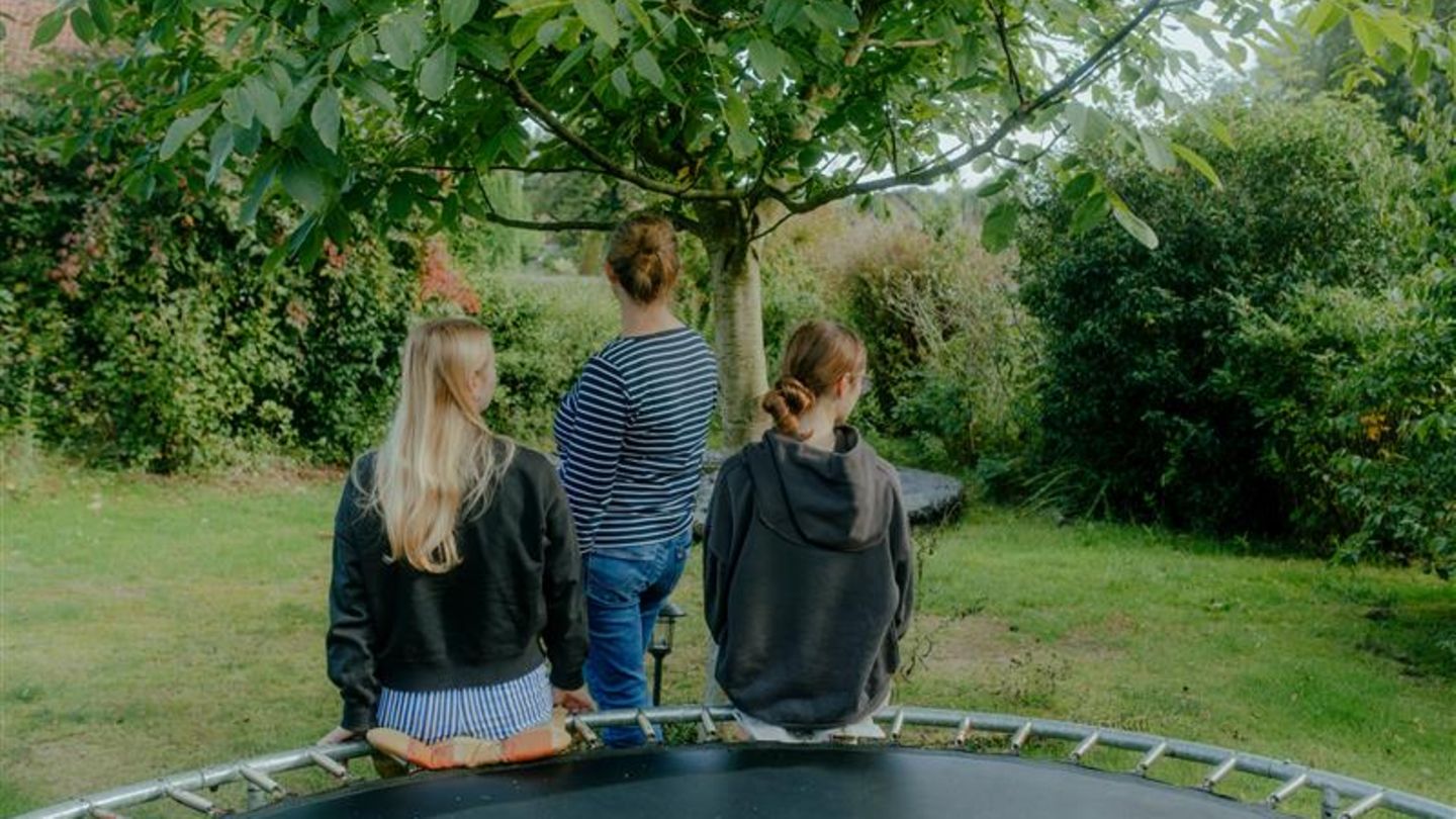 Mutter und Töchter mit Autismus-Spektrum-Störung: von hinten im Garten fotografiert