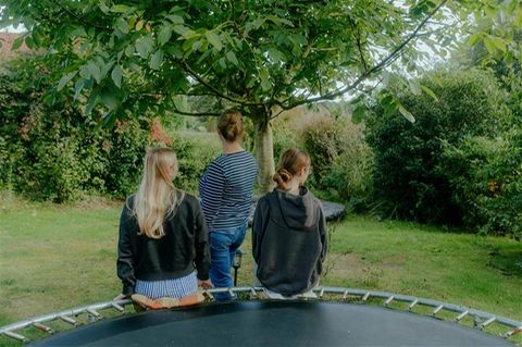 Mutter und Töchter mit Autismus-Spektrum-Störung: von hinten im Garten fotografiert