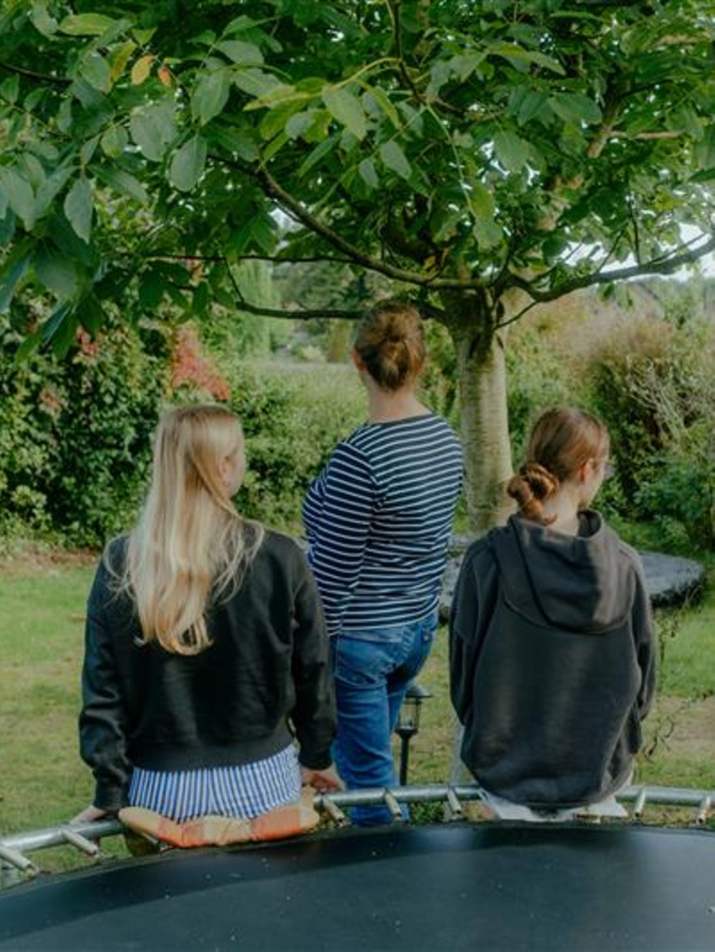 Mutter und Töchter mit Autismus-Spektrum-Störung: von hinten im Garten fotografiert