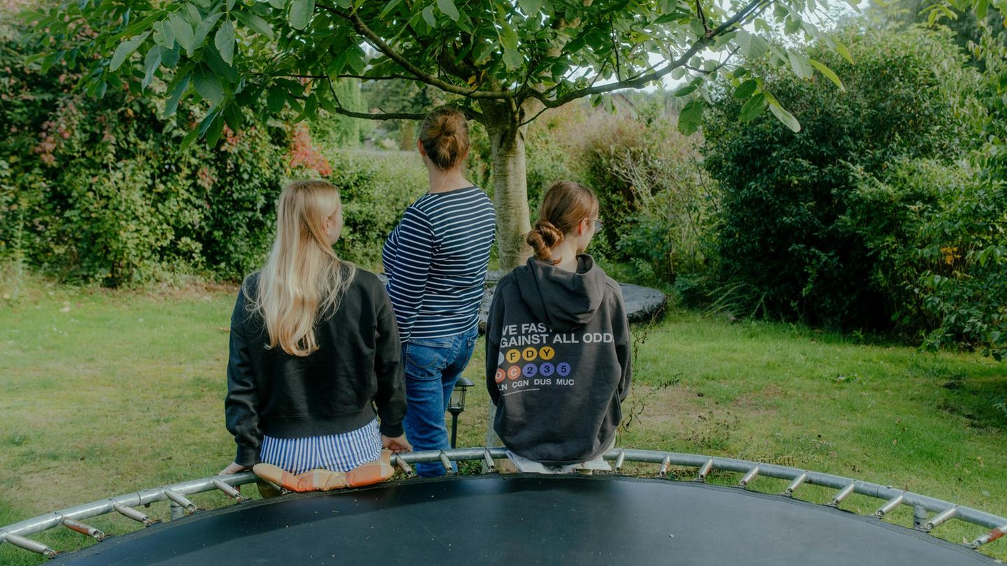 Mutter und Töchter mit Autismus-Spektrum-Störung: von hinten im Garten fotografiert