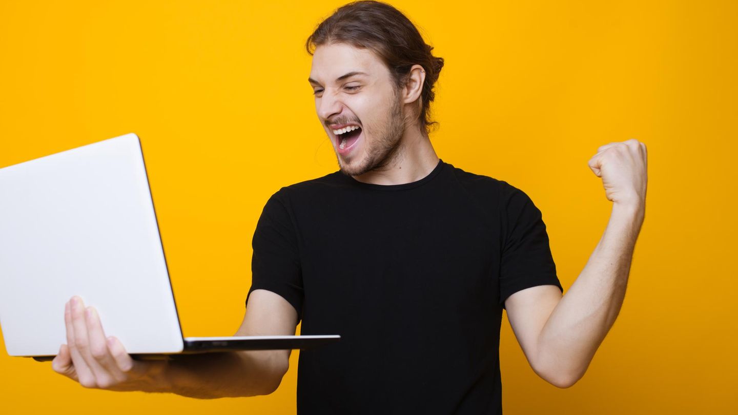 Laptop Black Friday: Ein Mann freut sich mit Laptop in der Hand über gute Angebote