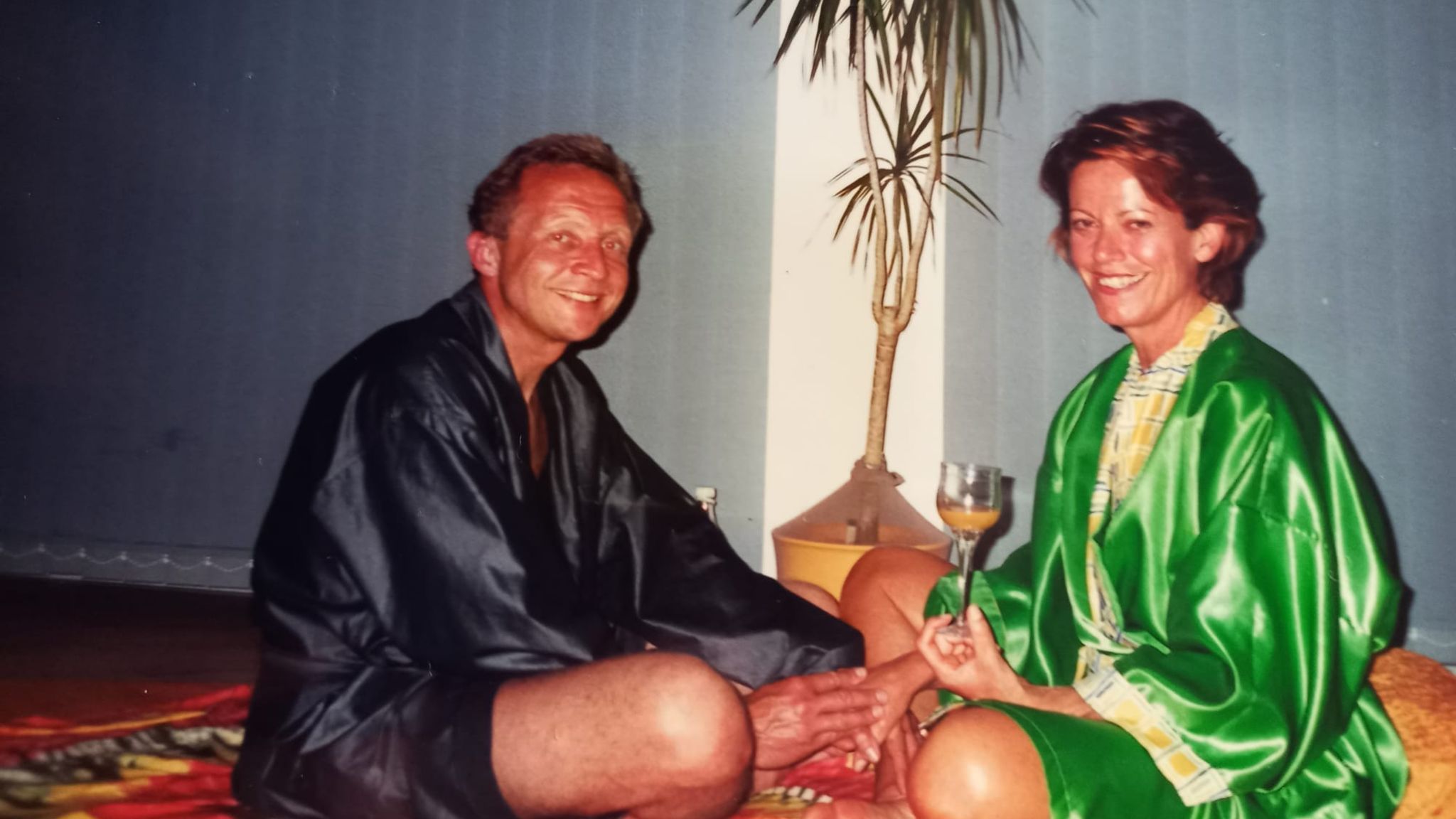 Sex im Alter: Ein Mann und eine Frau, beide leichtbekleidet, sitzen auf dem Boden und halten Händchen.