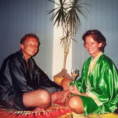 Sex im Alter: Ein Mann und eine Frau, beide leichtbekleidet, sitzen auf dem Boden und halten Händchen.