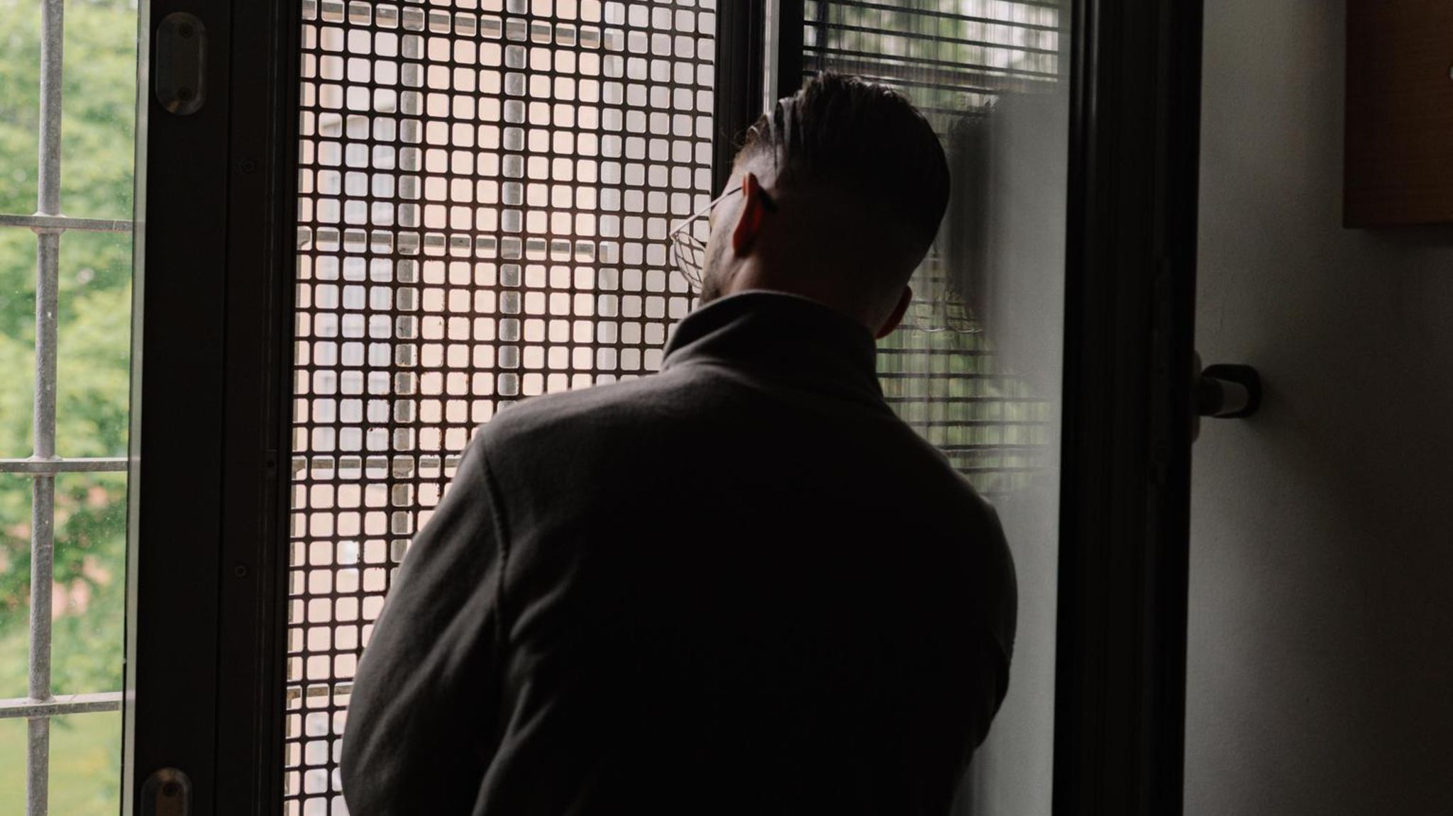 Mann vor einem Gitterfenster im Jugendgefängnis